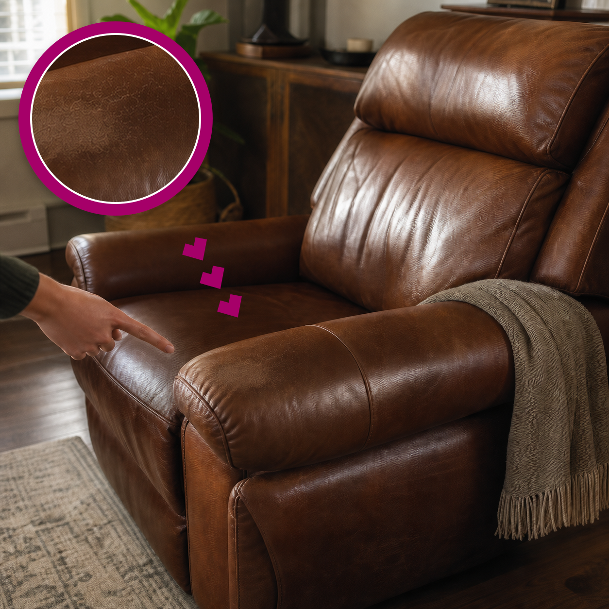 A soft friction scuff on a cognac-brown leather recliner armrest, highlighted with a matching magenta magnified close-up and a pointing hand.