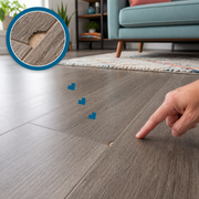 Small chip in a gray-brown laminate plank edge with a matching magnified close-up and a hand pointing nearby